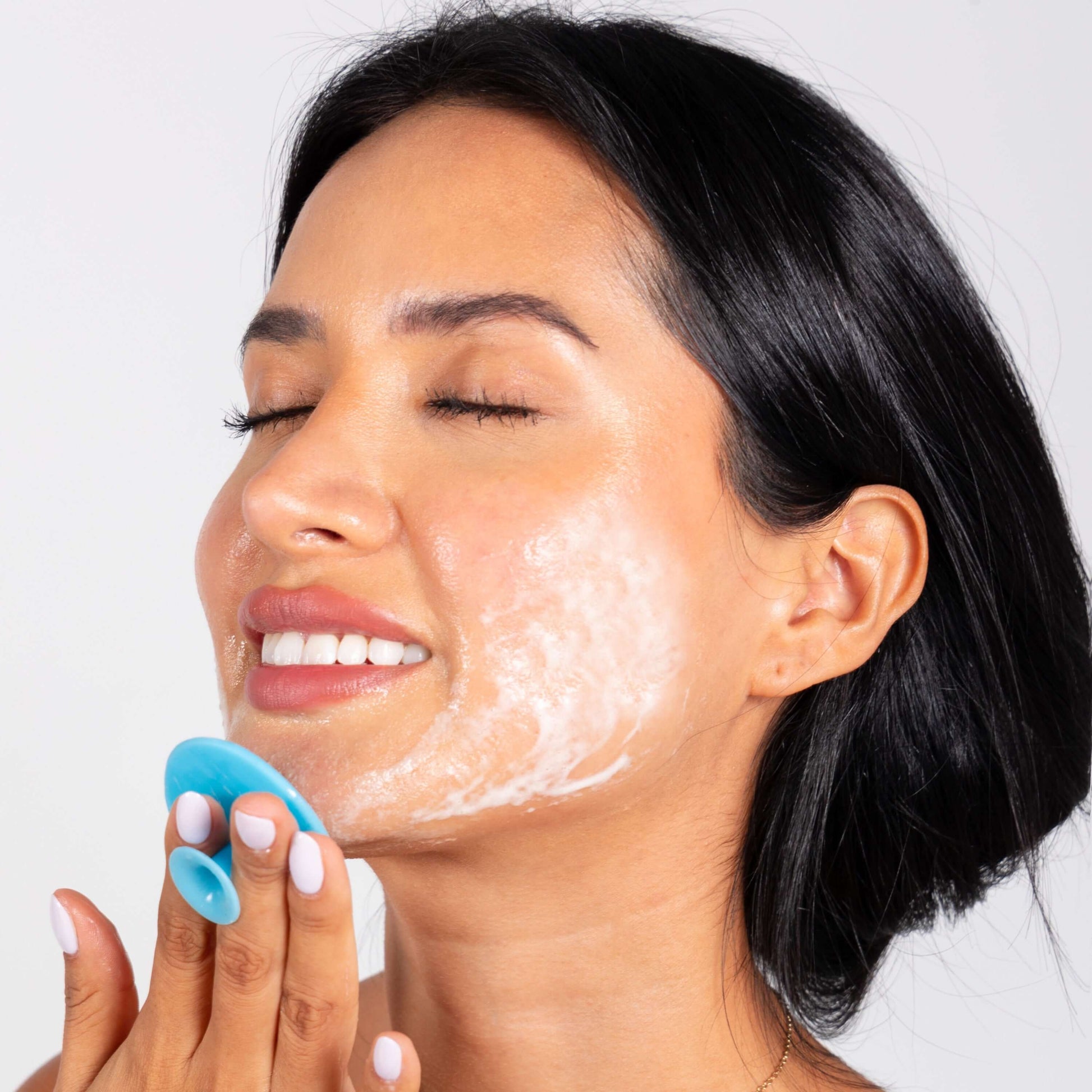Woman using Delune's Face Scrubber for gentle exfoliation and radiant skin with antimicrobial protection.
