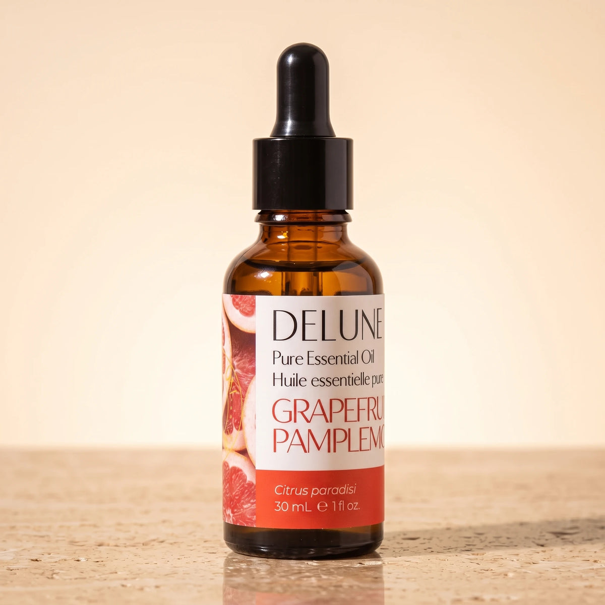 Delune Grapefruit (Pink) Pure Essential Oil, 30ml amber glass dropper bottle on warm travertine stone