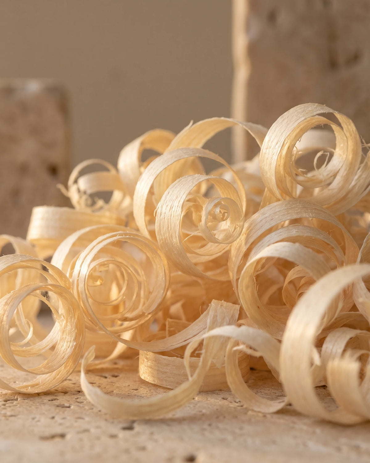 Delicate curls of pale ho wood shavings glowing in warm backlight — the soft, floral-woody scent of Delune Ho Wood Pure Essential Oil