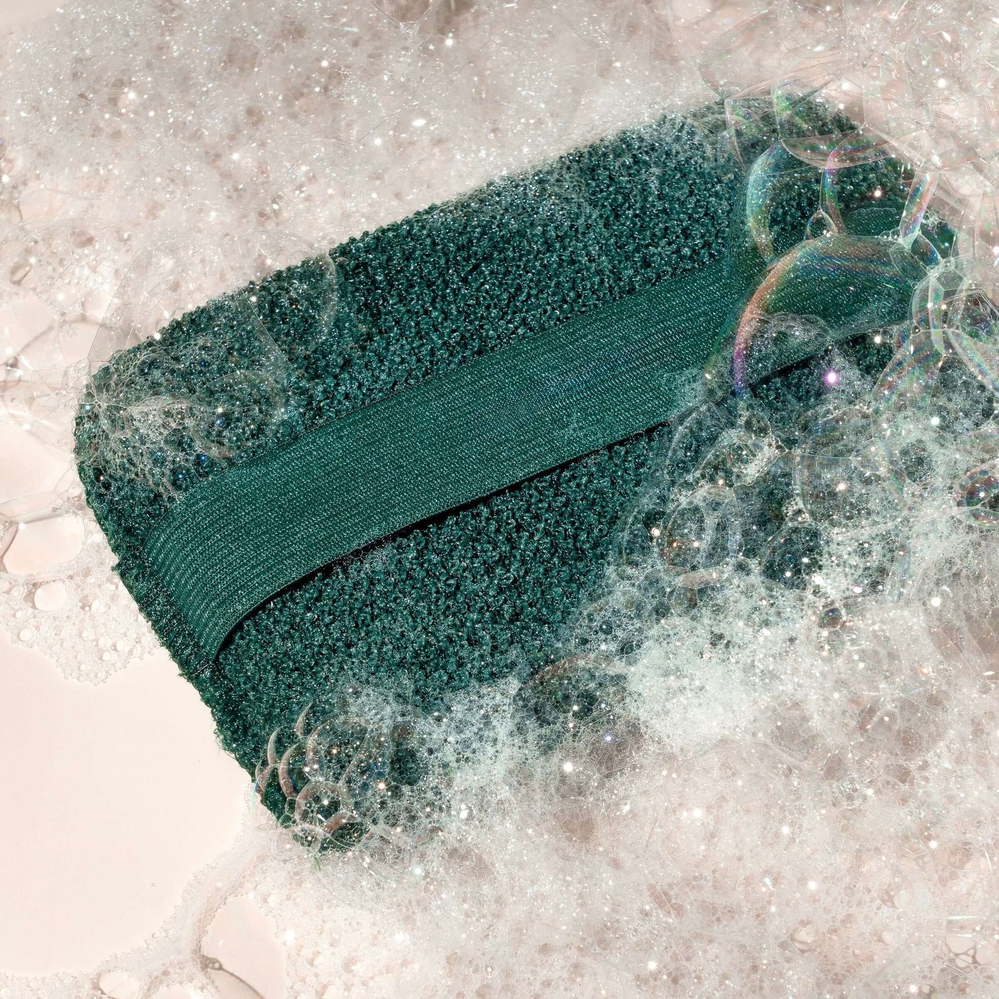 XL Body Buffer with strap, surrounded by soap suds. Sustainable exfoliating body scrubber for smooth skin. Perfect for bath or shower.