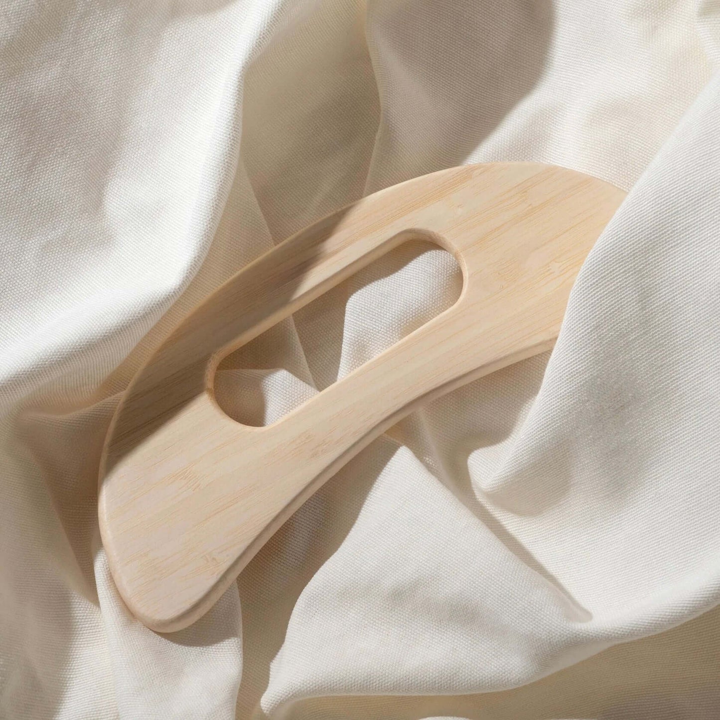 Delune Wooden Body Massager with ergonomic shape on soft fabric, ideal for reducing muscle tension and promoting relaxation.