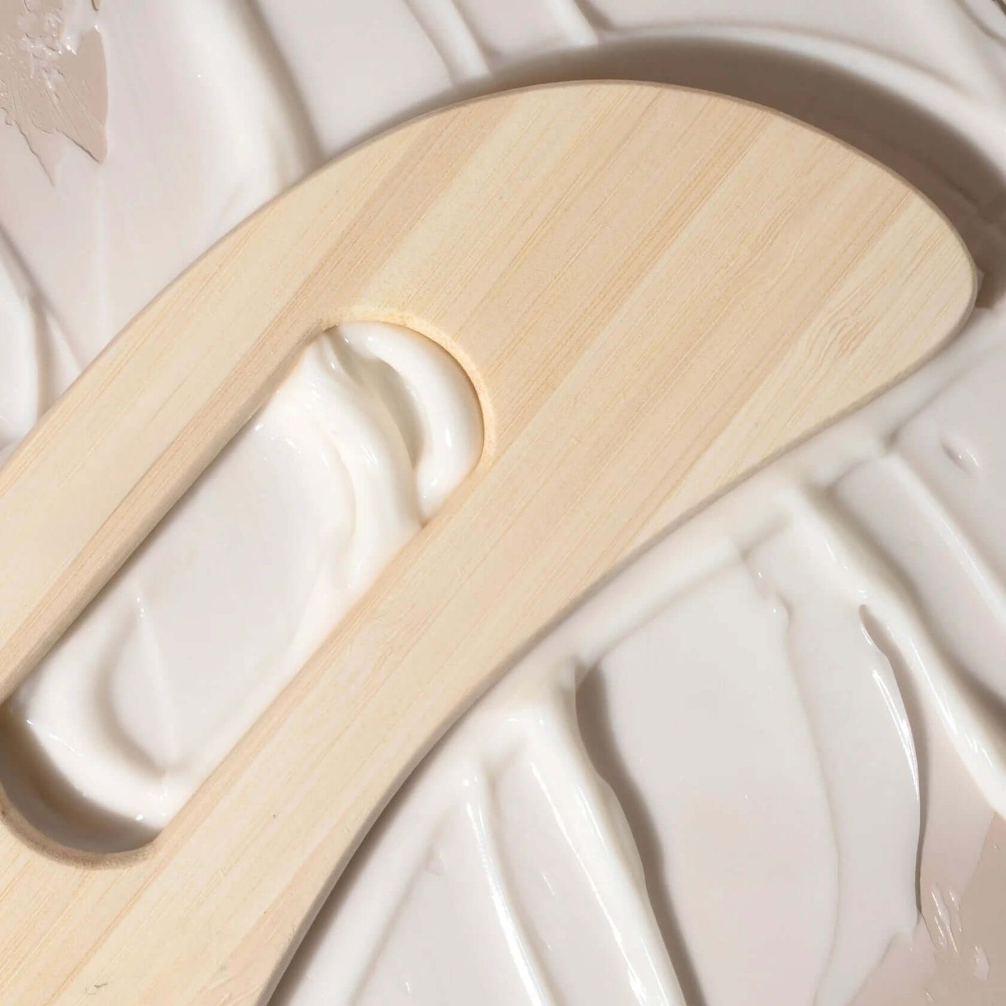 Elegant Delune Wooden Body Massager on smooth lotion surface, ideal for reducing muscle tension and promoting relaxation.