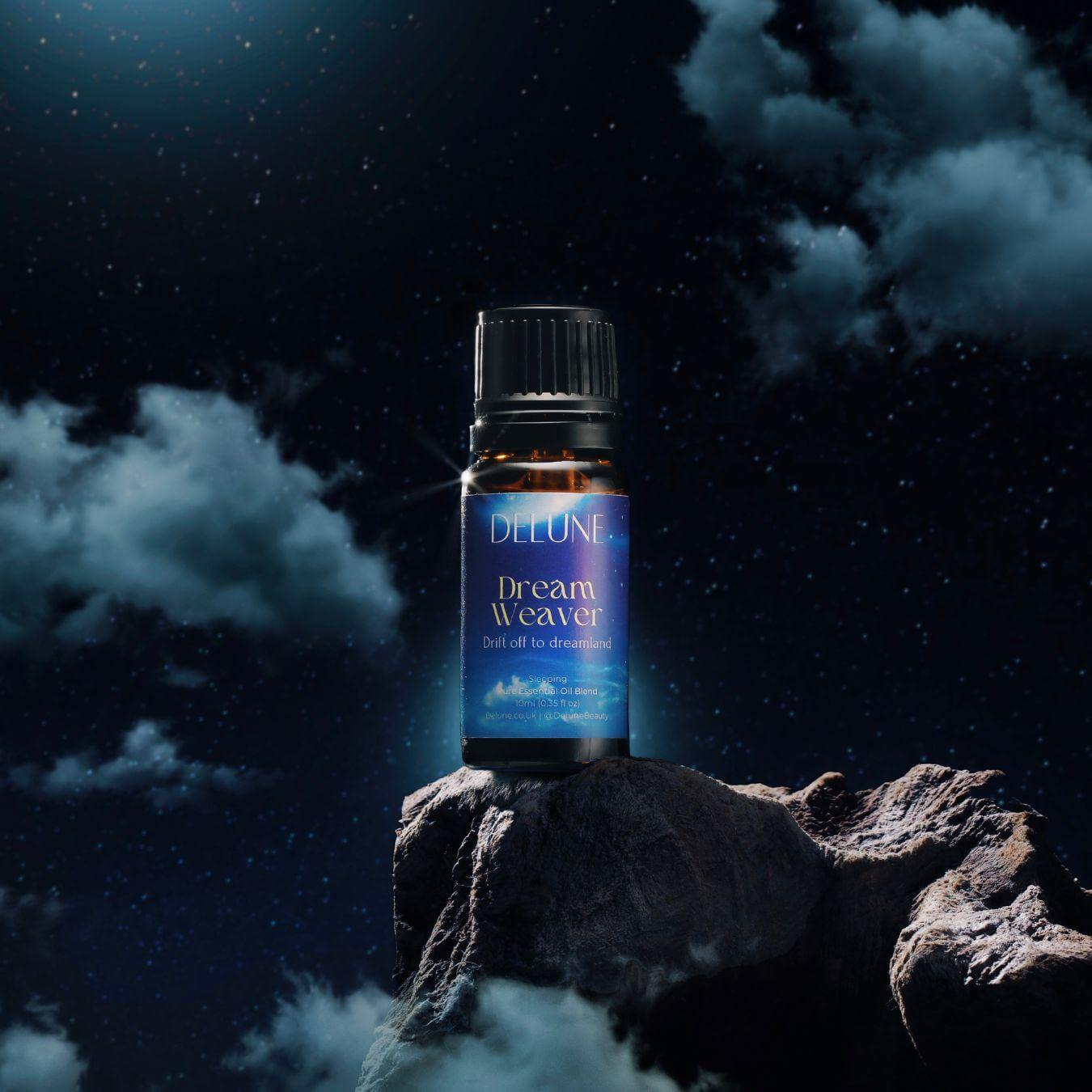Dream Weaver essential oil blend bottle on a rock with night sky, promoting sleep and relaxation with lavender and chamomile.