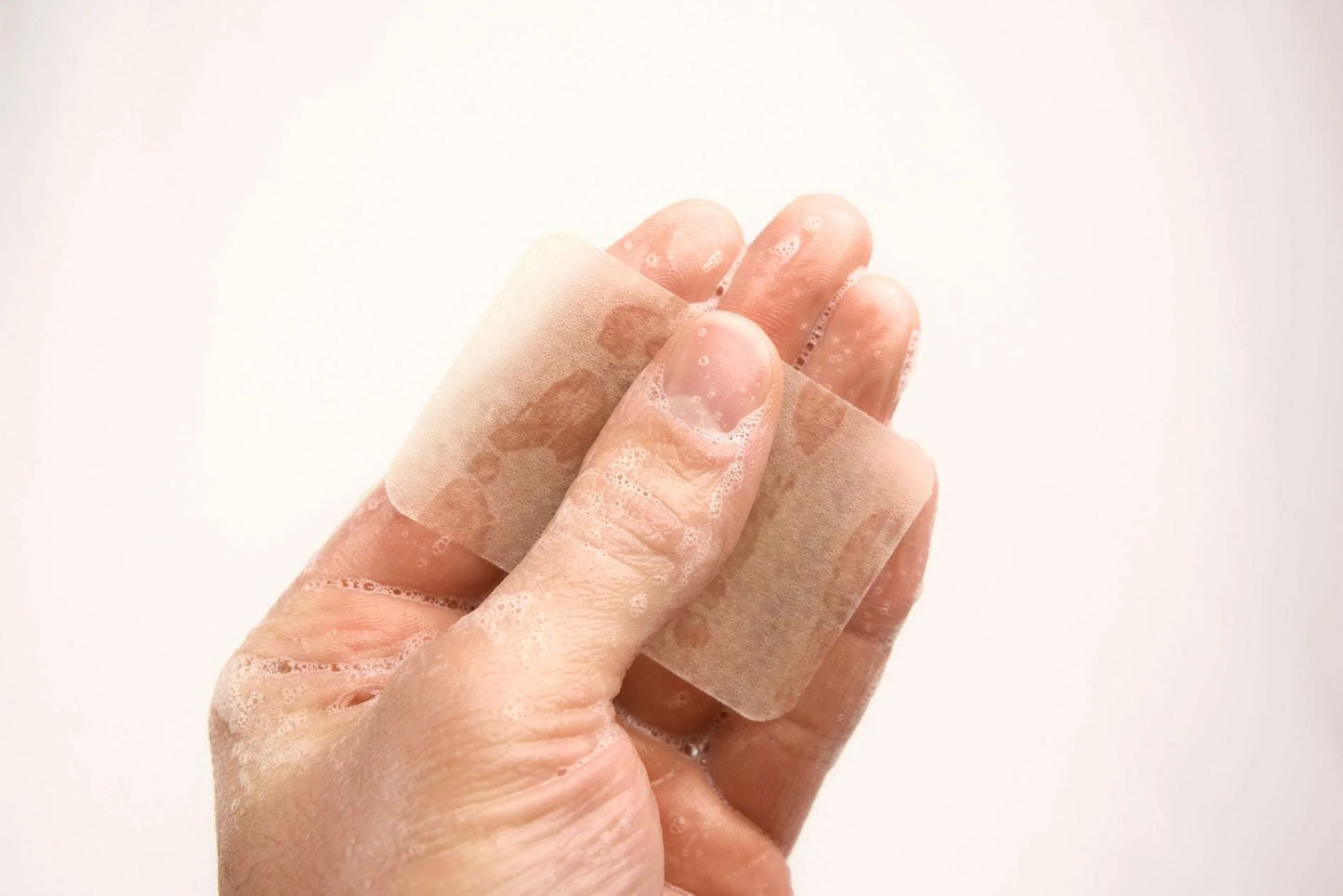 Person holding hand soap sheet, ready for water activation. Eco-friendly and chemical-free, perfect for travel. 40 washes per pack.