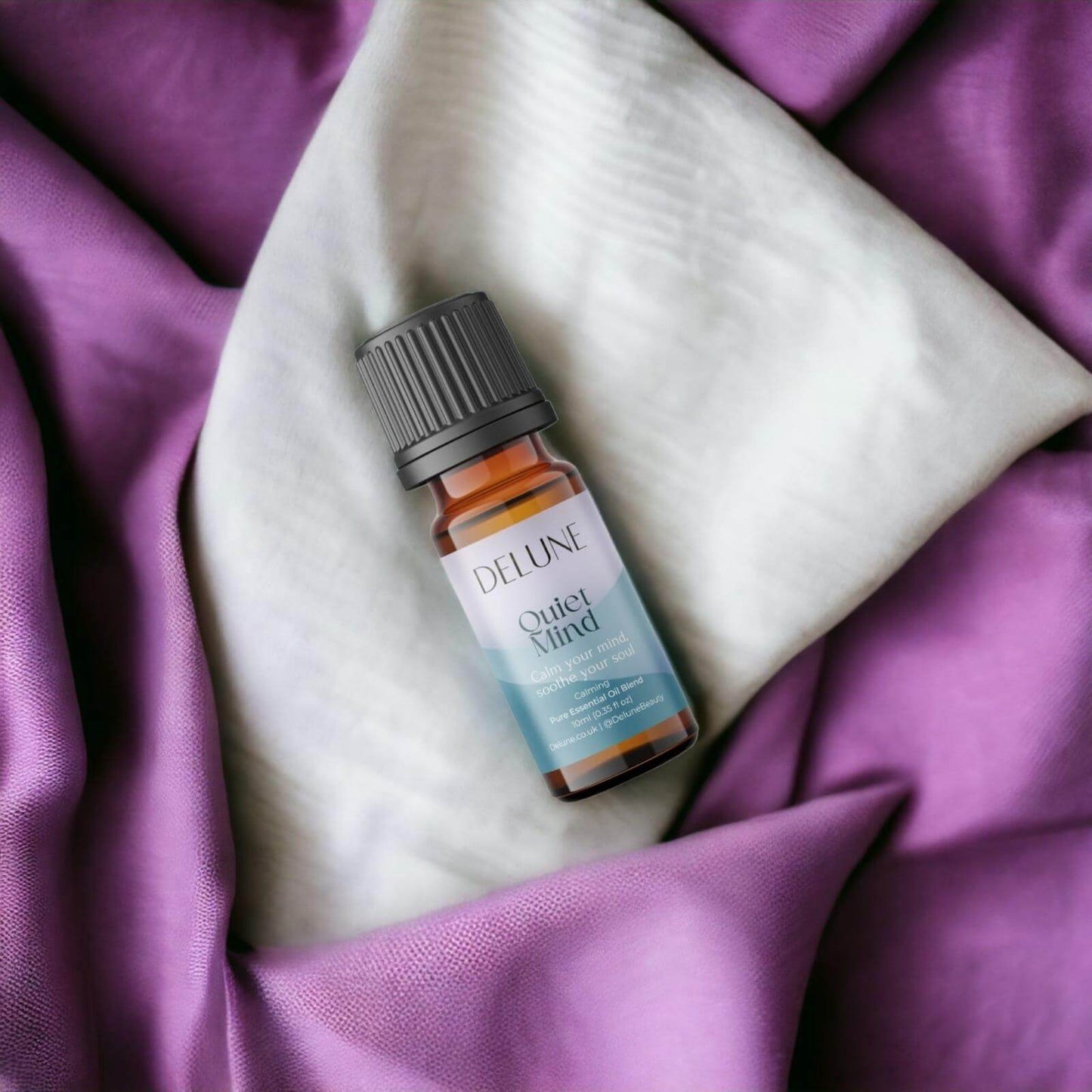 Quiet Mind Calm essential oil blend bottle on purple and white fabric, promoting relaxation and clarity with sandalwood and citrus.