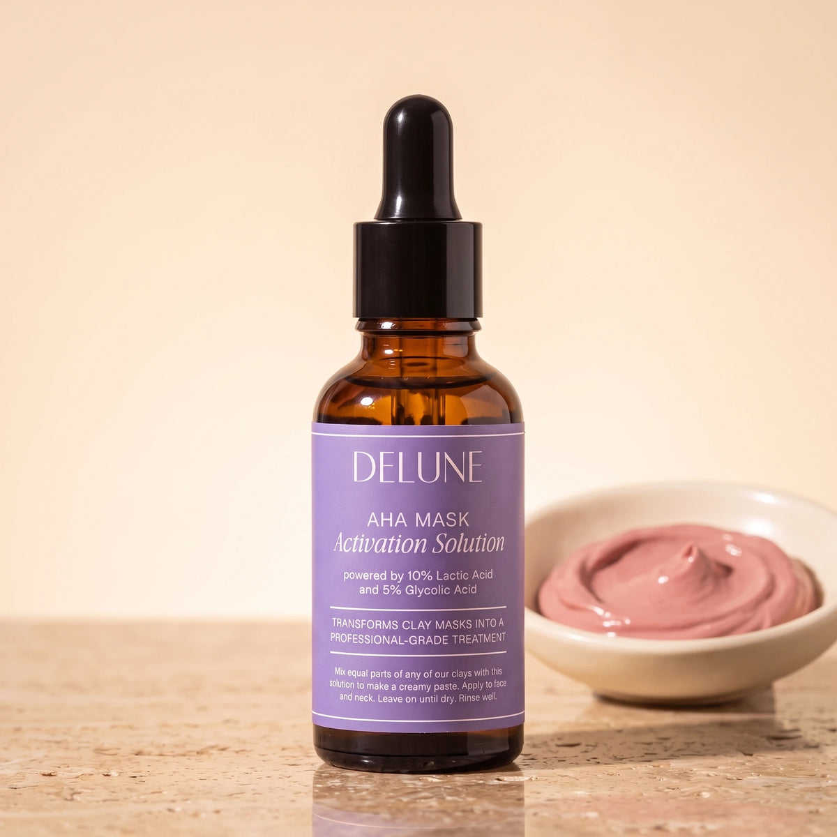 Mask activator UAE – Delune Dubai AHA Mask Activation Solution 30ml dropper bottle on travertine beside a dish of rose clay