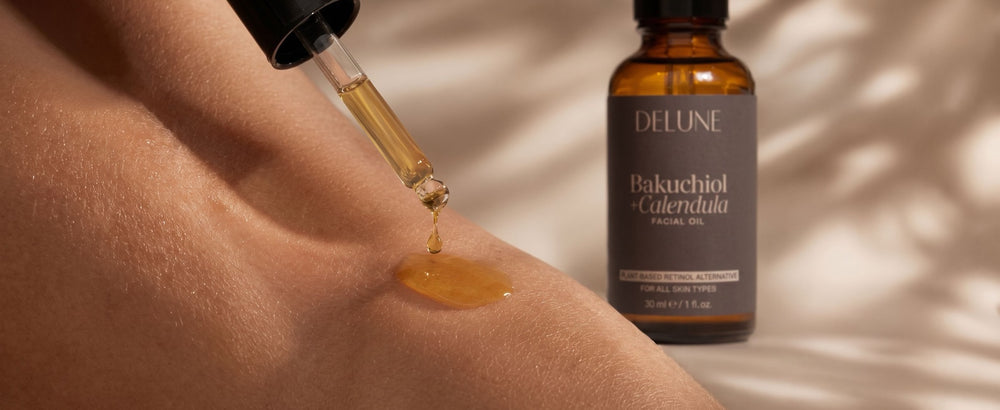 Golden facial oil falling from a pipette onto skin beside the Delune bottle