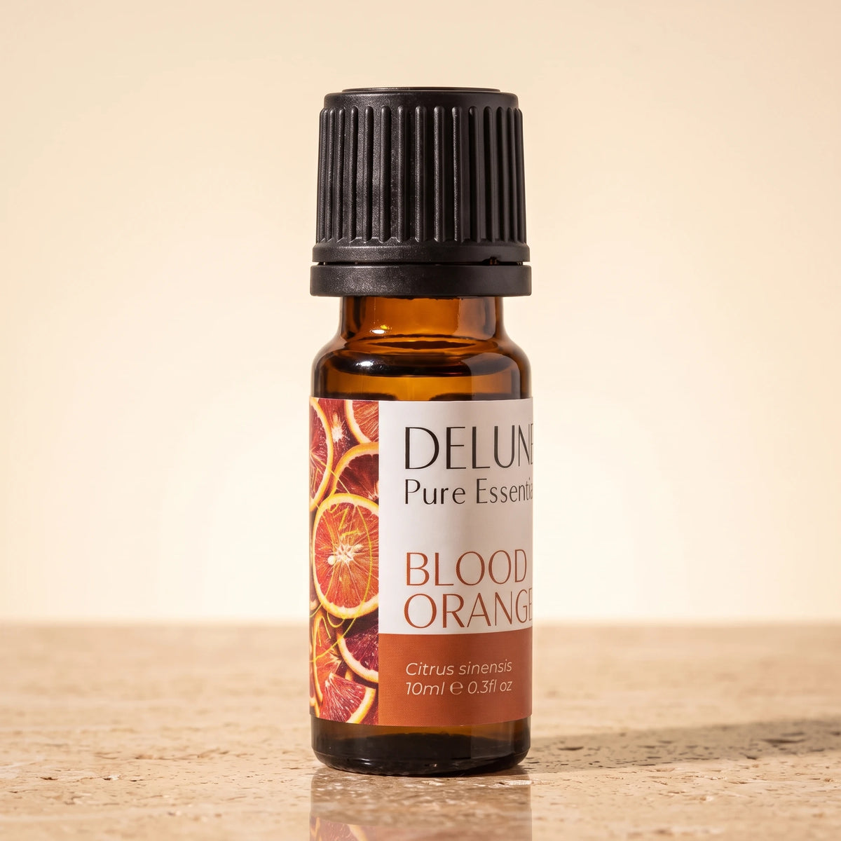 Delune Blood Orange Pure Essential Oil, 10ml amber glass bottle on warm travertine stone