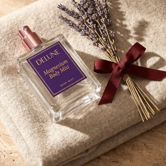 Magnesium Body Mist resting on a folded oatmeal wool throw beside dried lavender tied with an oxblood ribbon
