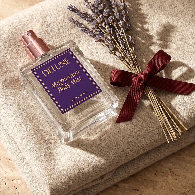 Magnesium Body Mist resting on a folded oatmeal wool throw beside dried lavender tied with an oxblood ribbon