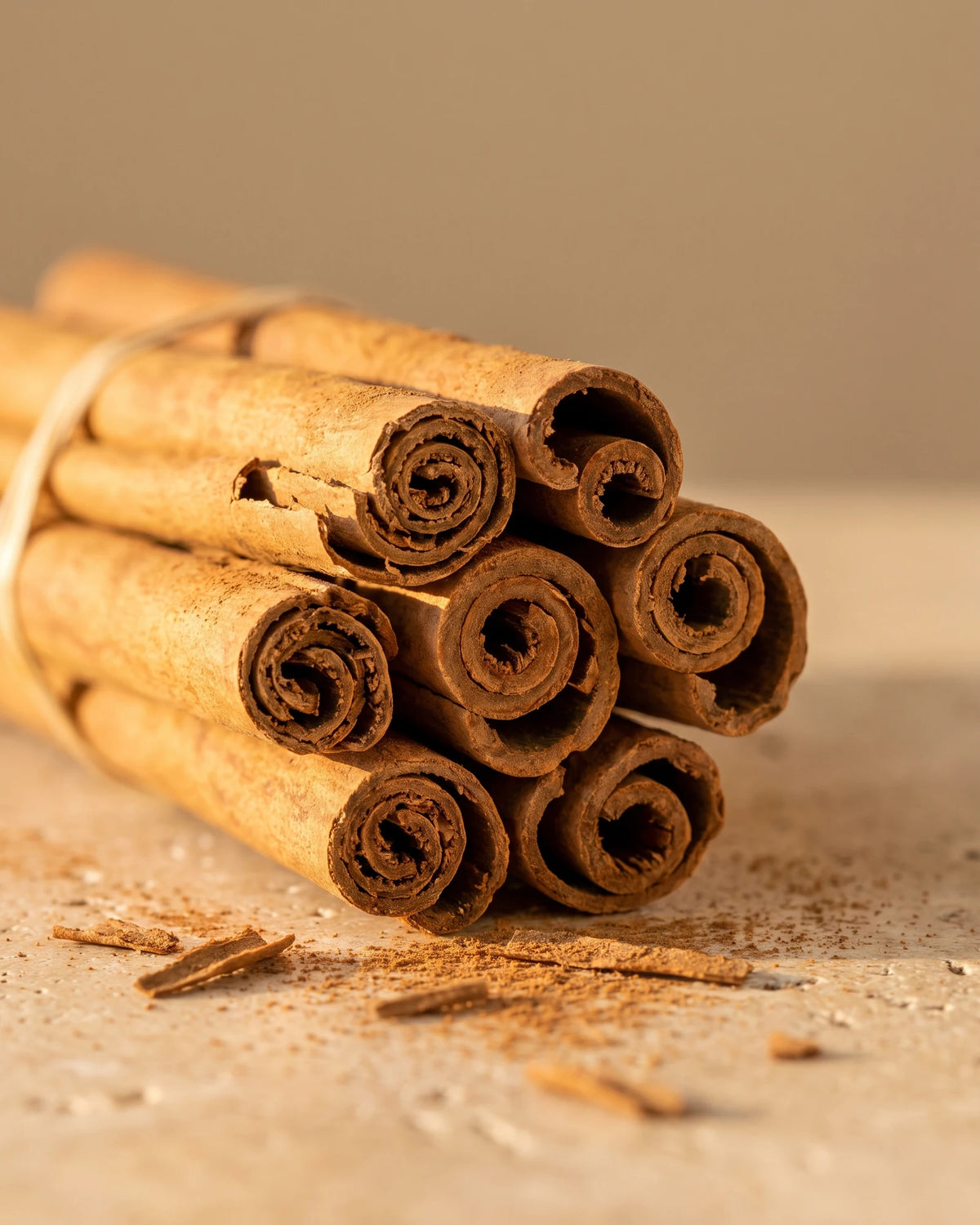 Cinnamon essential oil UAE – Delune Dubai: a bundle of cinnamon quills with a dusting of ground cinnamon on travertine