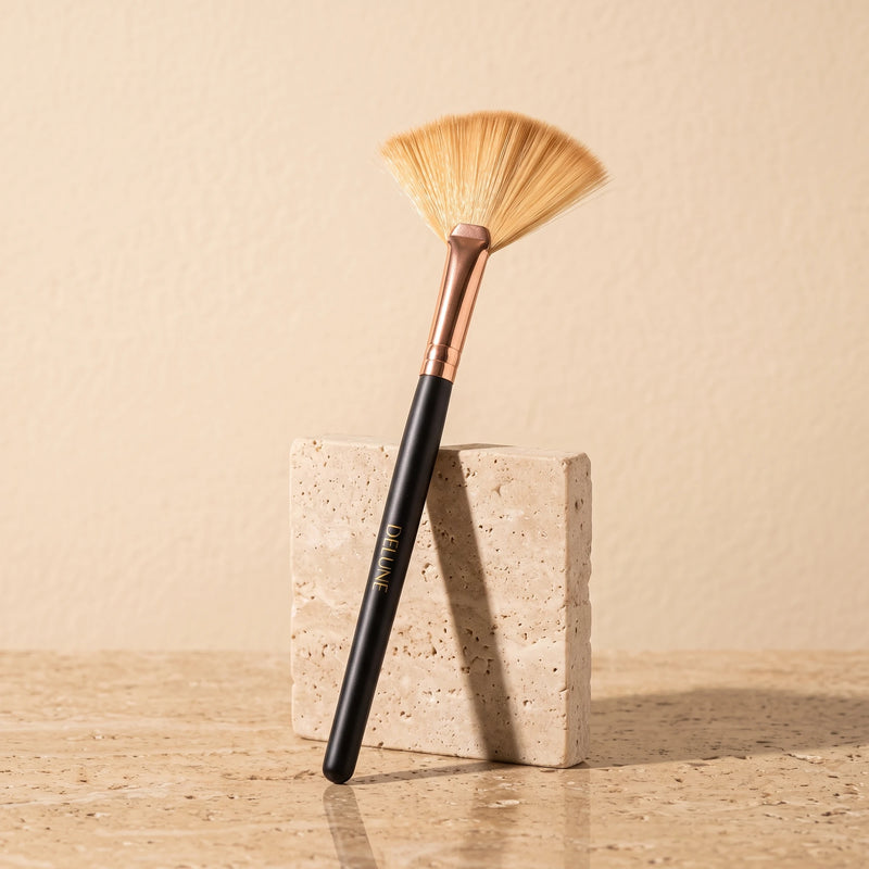 Facial tool UAE – Delune Dubai clay mask fan brush with rose-gold ferrule leaning on a travertine block