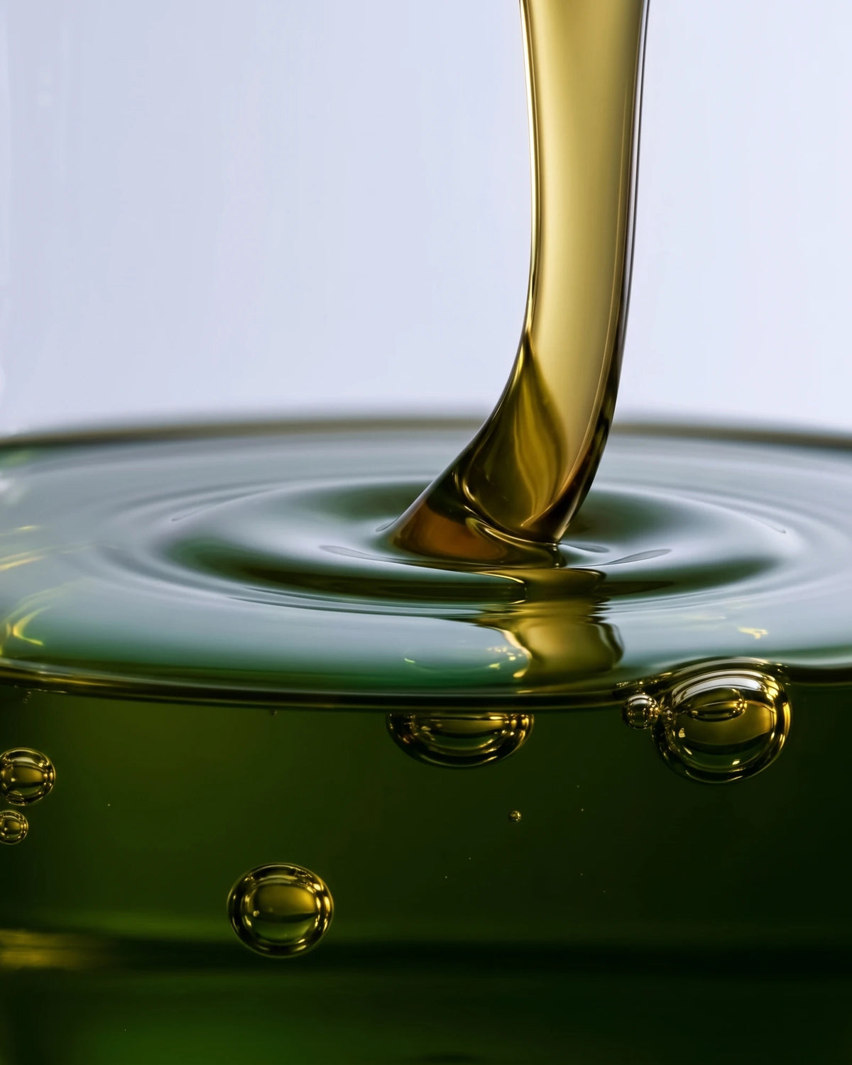 Face serum UAE – Delune Dubai Clear 49% Tamanu Oil Serum texture: green-gold tamanu oil pouring into a pool with soft ripples