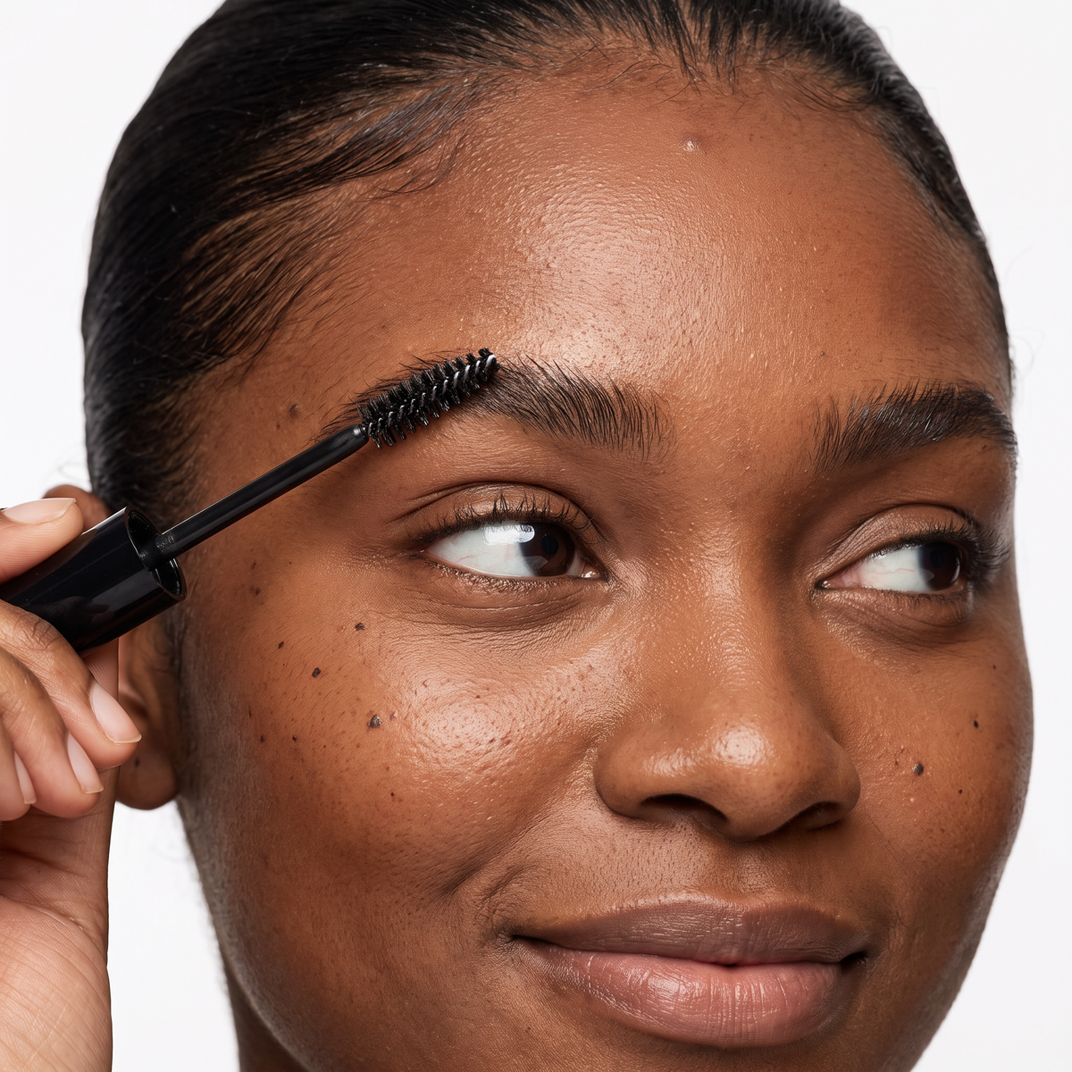 Brushing brows upward with the spoolie of Delune Dubai Clear Brow Sculpt Gel