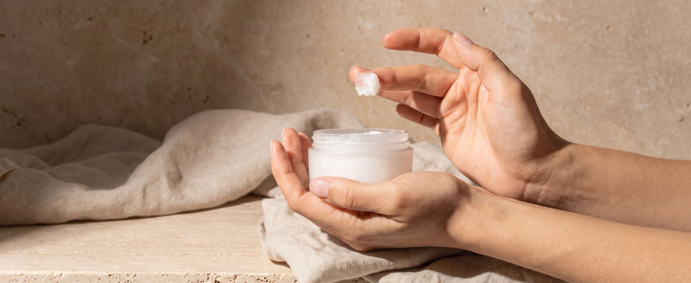 Raw coconut cream cleanser scooped from the jar in soft warm light