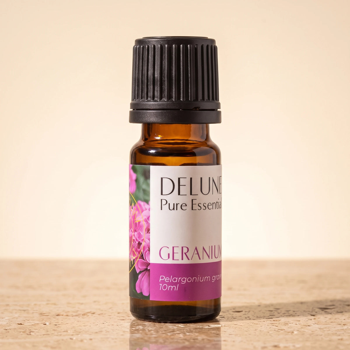 Delune Geranium Pure Essential Oil, 10ml amber glass bottle on warm travertine stone