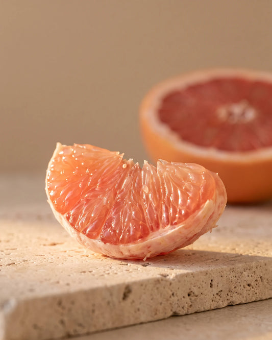Grapefruit essential oil UAE – Delune Dubai: a glistening pink grapefruit segment backlit by warm sunlight