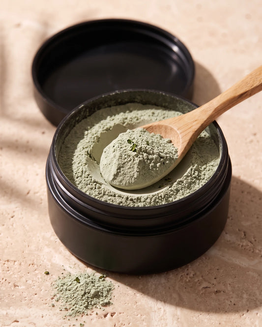 Clay face mask UAE – Open jar of Delune Dubai Green Tea Clay showing the soft dry sage-green clay powder with a wooden spoon