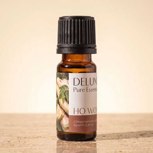 Delune Ho Wood Pure Essential Oil, 10ml amber glass bottle on warm travertine stone