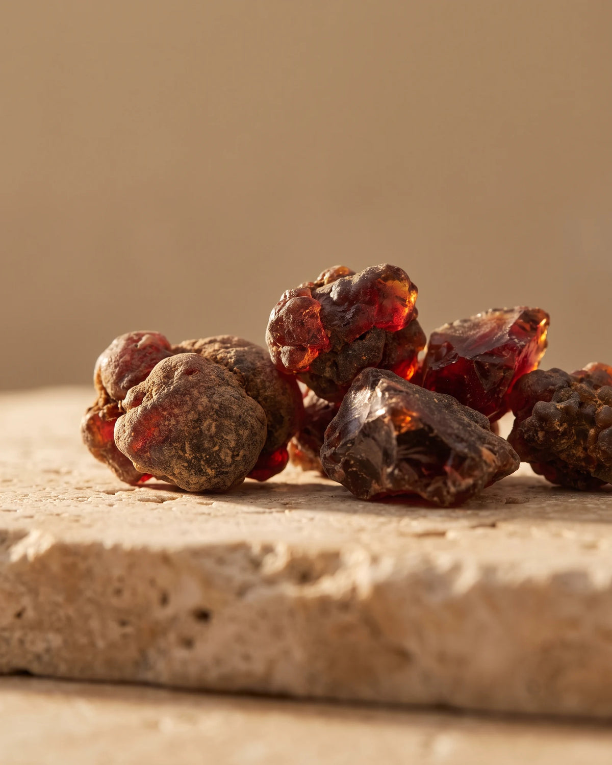 Myrrh essential oil UAE – Delune Dubai: raw myrrh resin pieces glowing deep garnet in warm backlight