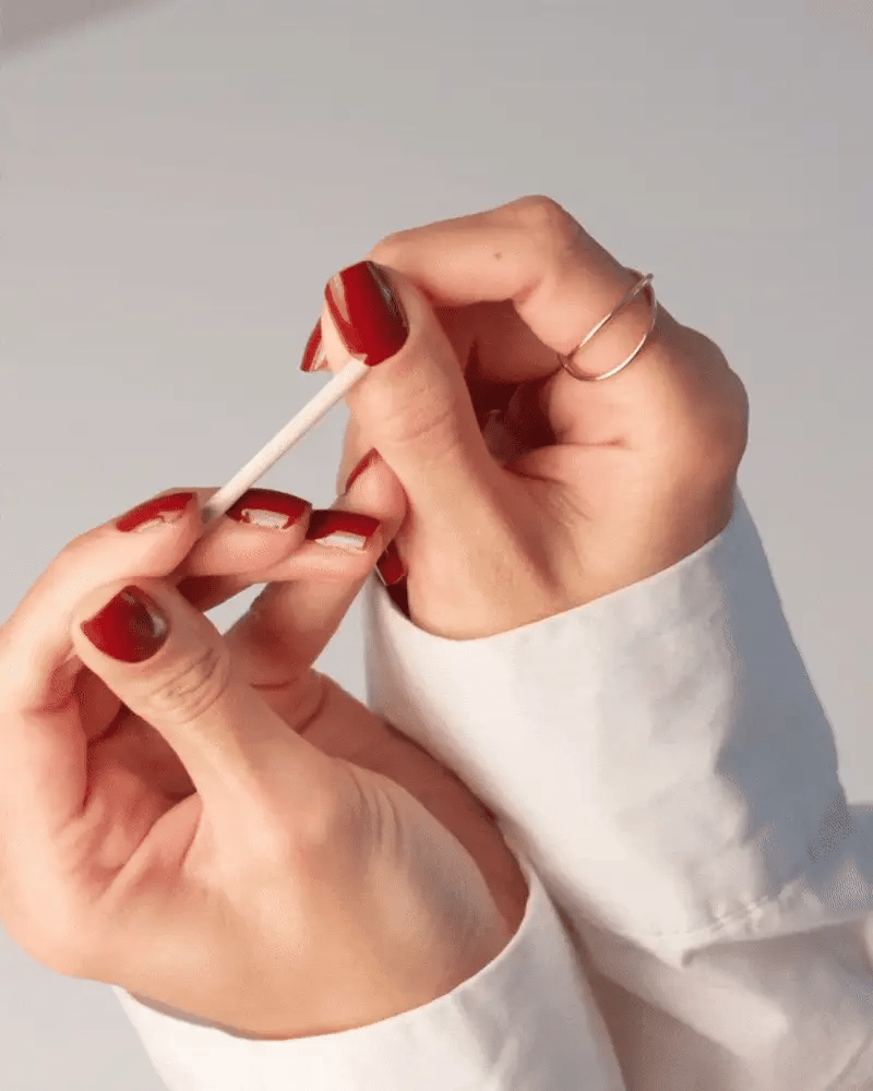 Lifting a Delune nail wrap gently with a wooden stick after cuticle oil