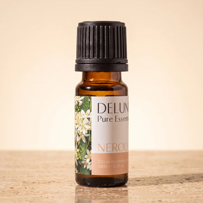 Delune Neroli Pure Essential Oil, 10ml amber glass bottle on warm travertine stone