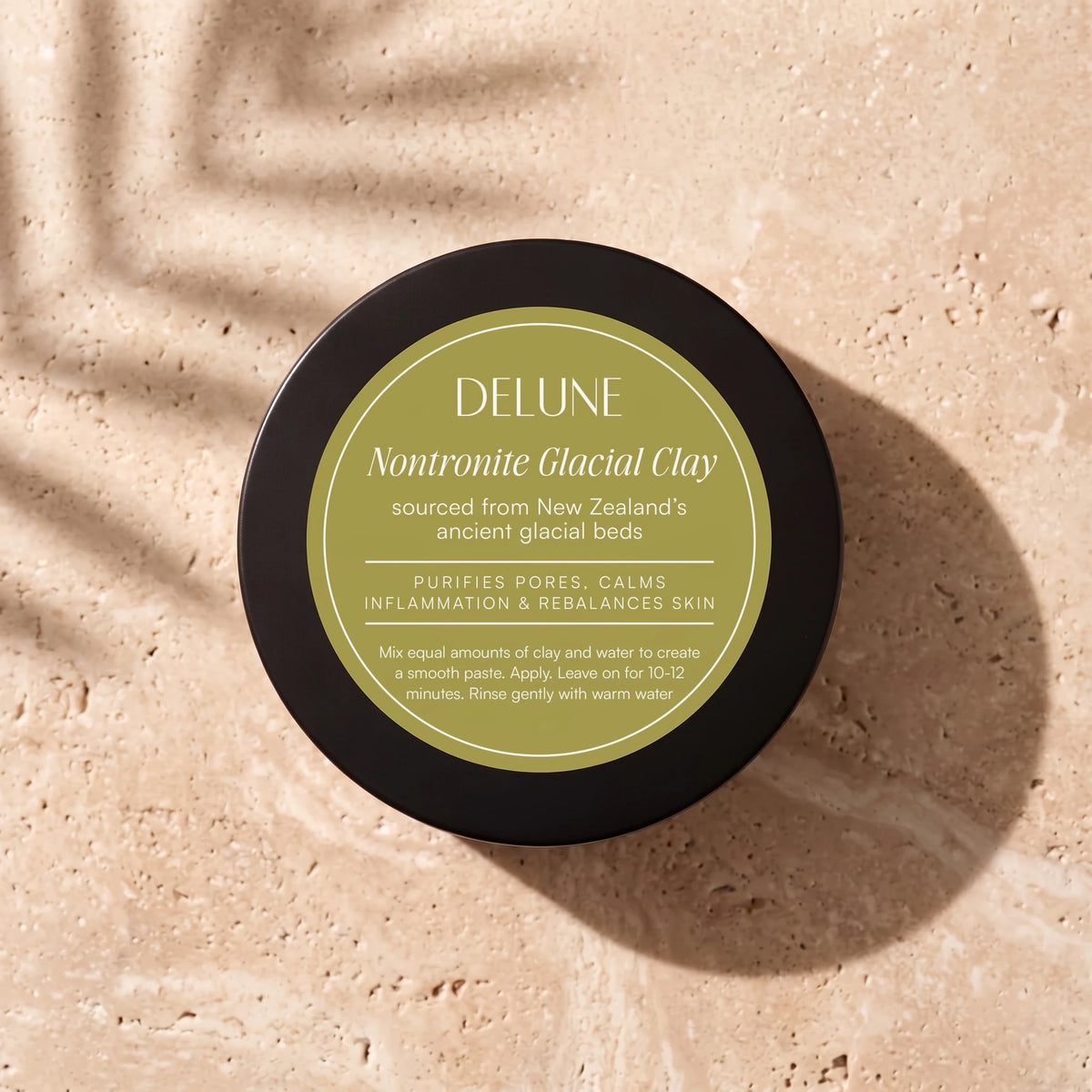 Clay face mask UAE – Delune Dubai Nontronite Glacial Clay Mask jar from above on warm travertine in soft window light
