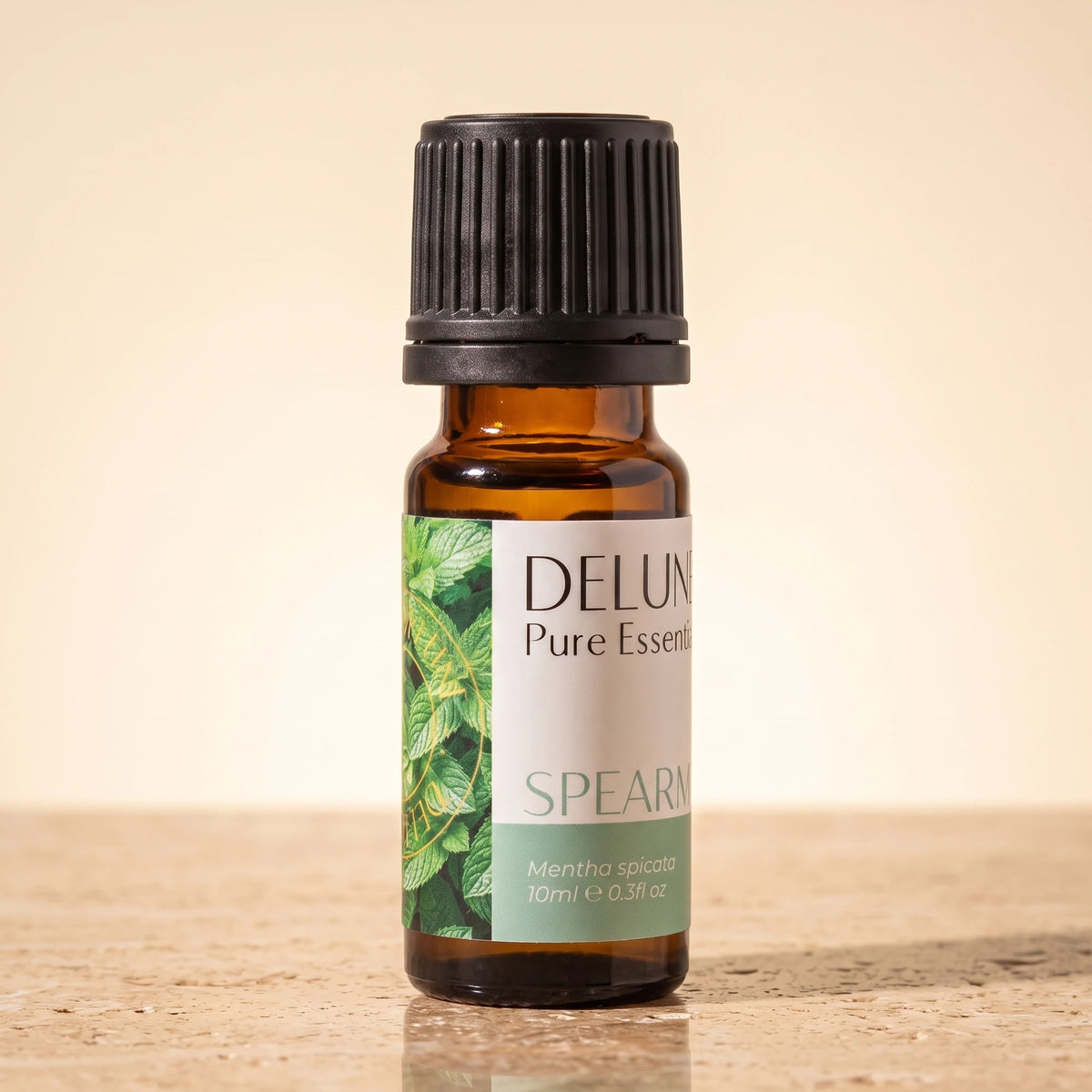 Delune Spearmint Pure Essential Oil, 10ml amber glass bottle on warm travertine stone