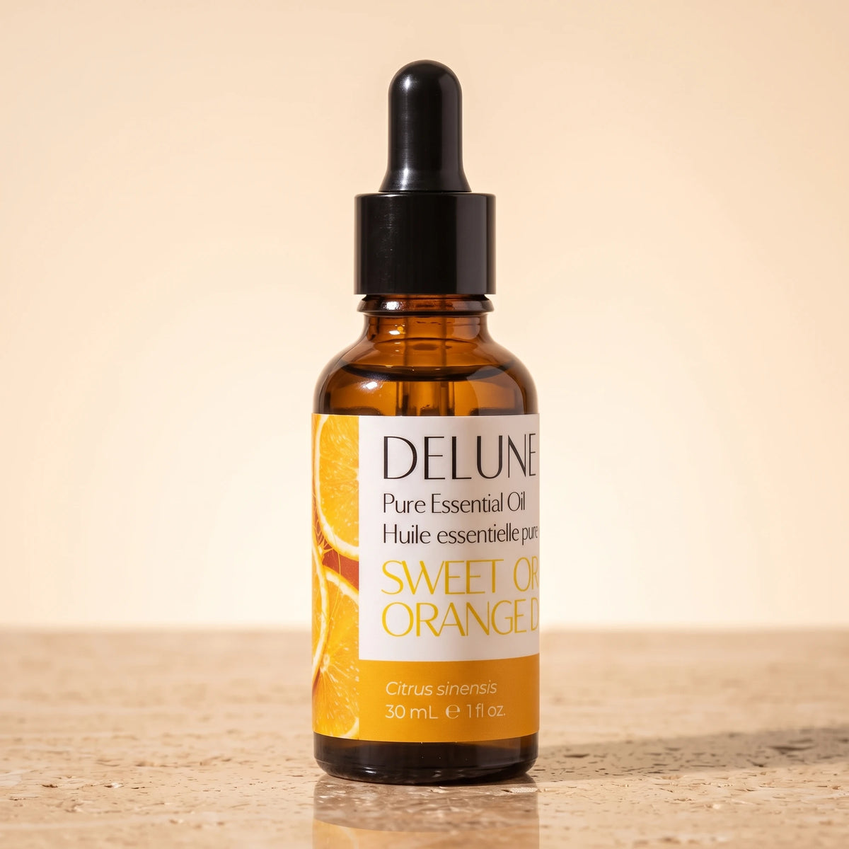 Delune Sweet Orange Pure Essential Oil, 30ml amber glass dropper bottle on warm travertine stone