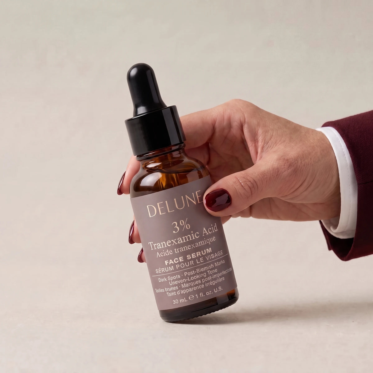 Hand picking up Delune Tranexamic Acid Serum