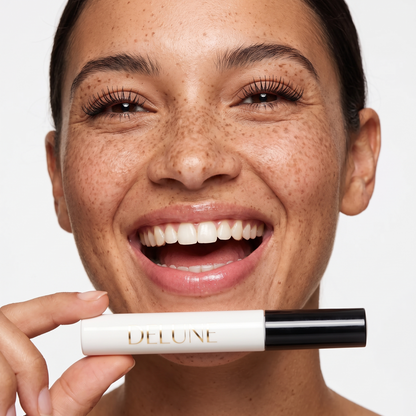 Model laughing with lifted lashes, holding Delune Dubai Tubing Mascara