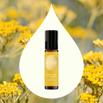 Helichrysum Essential Oil Roll-On bottle in front of blooming yellow flowers, symbolizing renewal and resilience.